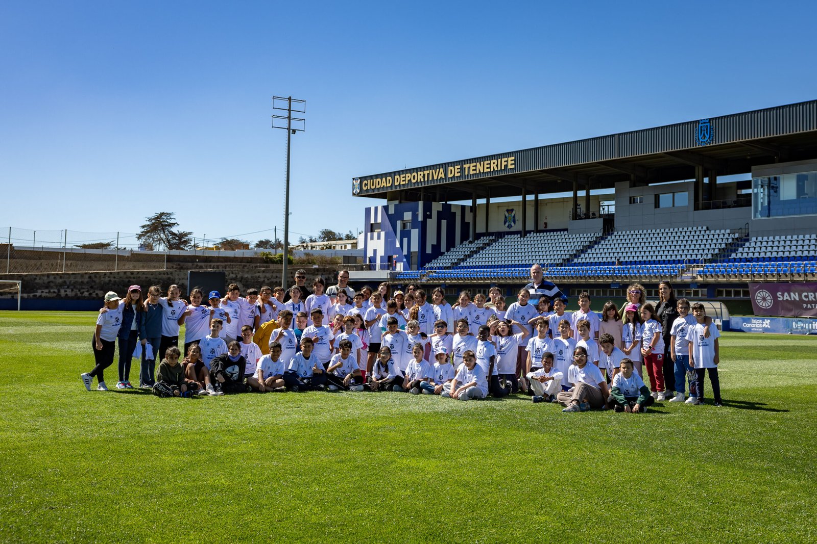 Escolares del CEIP Cabo Blanco en la vigésimo quinta sesión del proyecto CD Tenerife: Seña de identidad

Setenta y ocho alumnos y alumnas de Primaria conocen el universo blanquiazul a través del Heliodoro Rodríguez López y la Ciudad Deportiva de Tenerife Javier Pérez.

El Heliodoro Rodríguez López y la Ciudad Deportiva de Tenerife Javier Pérez acogieron la vigésimo quinta jornada del proyecto ‘CD Tenerife: Seña de identidad’, que se desarrolla por segundo curso consecutivo con la organización de la Fundación CD Tenerife, el patrocinio del Gobierno de Canarias y la colaboración, en este caso, del Ayuntamiento de Arona.

Así, un total de 78 estudiantes del CEIP Cabo Blanco, del barrio homónimo, disfrutaron de esta experiencia en clave blanquiazul, que acerca la entidad a escolares de entre nueve y once años, mostrando los valores que el CD Tenerife aporta al fútbol de la Isla.

Como es habitual, la visita al Estadio arrancó en el antiguo pórtico de la grada de Herradura con la entonación del ‘Riqui-raca’, el popular cántico de ánimo de los aficionados tinerfeñistas. Luego continuó el recorrido por distintos espacios del coliseo capitalino: sala de prensa, campo de juego, vestuarios o banquillos, entre otros. La coordinadora del proyecto, Priscila Díaz, guio a alumnos y profesores en su recorrido.

Llegados a las instalaciones de tecnificación de Geneto-Los Baldíos (La Laguna), los participantes fueron recibidos por Quique Medina (secretario técnico del Área de Fútbol Base del CD Tenerife) y interactuaron con los jugadores profesionales Aitor Sanz, Sergio González y Fabio, además de conocer los espacios de trabajo del primer equipo blanquiazul y su cadena de filiales.

La segunda fase de ‘CD Tenerife: Seña de identidad’ se extenderá hasta el próximo mes de junio (martes y jueves de cada semana), periodo en el que se espera la visita de alumnado de cuarto y quinto de Primaria de centros de enseñanza de siete municipios sureños: Adeje, Arona, Vilaflor de Chasna, San Miguel de Abona, Granadilla de Abona, Arico y Fasnia.

Los niños y niñas tienen la oportunidad de visitar tanto el Estadio Heliodoro Rodríguez López como la Ciudad Deportiva de Tenerife Javier Pérez, donde, a través de DiSAFÍO, proyecto de la Fundación CD Tenerife, Fundación UD Las Palmas y el Gobierno de Canarias, se imparte una charla a los y las jóvenes sobre la inclusión en el deporte. La actividad cuenta con la colaboración de los siete ayuntamientos a los que pertenecen los colegios que participan en esta segunda ronda.

Este proyecto no solo busca fomentar el interés por el deporte, sino también fortalecer los lazos comunitarios y educativos. La experiencia enriquecedora involucra a los escolares, a los clubes y a la comunidad en general. Con el CD Tenerife como emblema, la Isla se acerca a la fascinante experiencia de combinar el fútbol y la educación.
