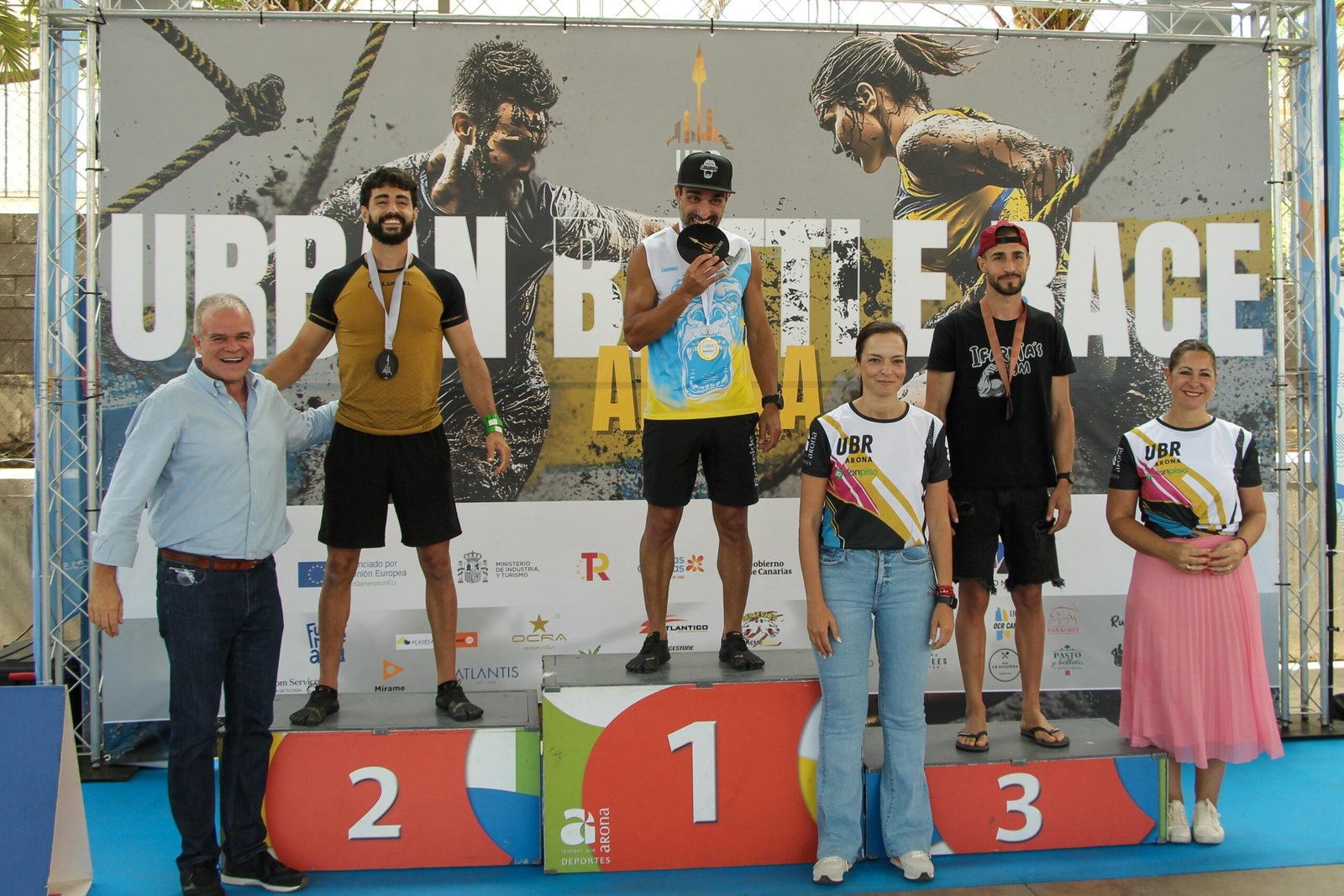 El cierre de la Primera Edición de la Urban Battle Race fue brutal y exitoso, con una gran participación. El evento contó con el apoyo del Ayuntamiento de Arona, a través de las concejalías de Turismo y Deportes, y el Área de Deportes del Cabildo, a través de IDECO «Tenerife Despierta Emociones». La carrera urbana de obstáculos tuvo un 41,7% de participación femenina e incluyó más de 50 obstáculos infernales en distintas modalidades. El evento contó con la presencia de 600 corredores y fue avalado por un equipo de 80 personas, incluidos voluntarios, organizadores y Marshalls de Ocra España. Los ganadores en las categorías Elite 12k femenina y masculina fueron Beatriz Rubio, Ifara Pérez, Carla Vega, Javier Rodríguez de León, Onán Medina y Ayoze Hernández González. Este evento consolida a Arona como un destino ideal para competiciones deportivas de alto nivel. ¡La Urban Battle Race ha llegado para quedarse!