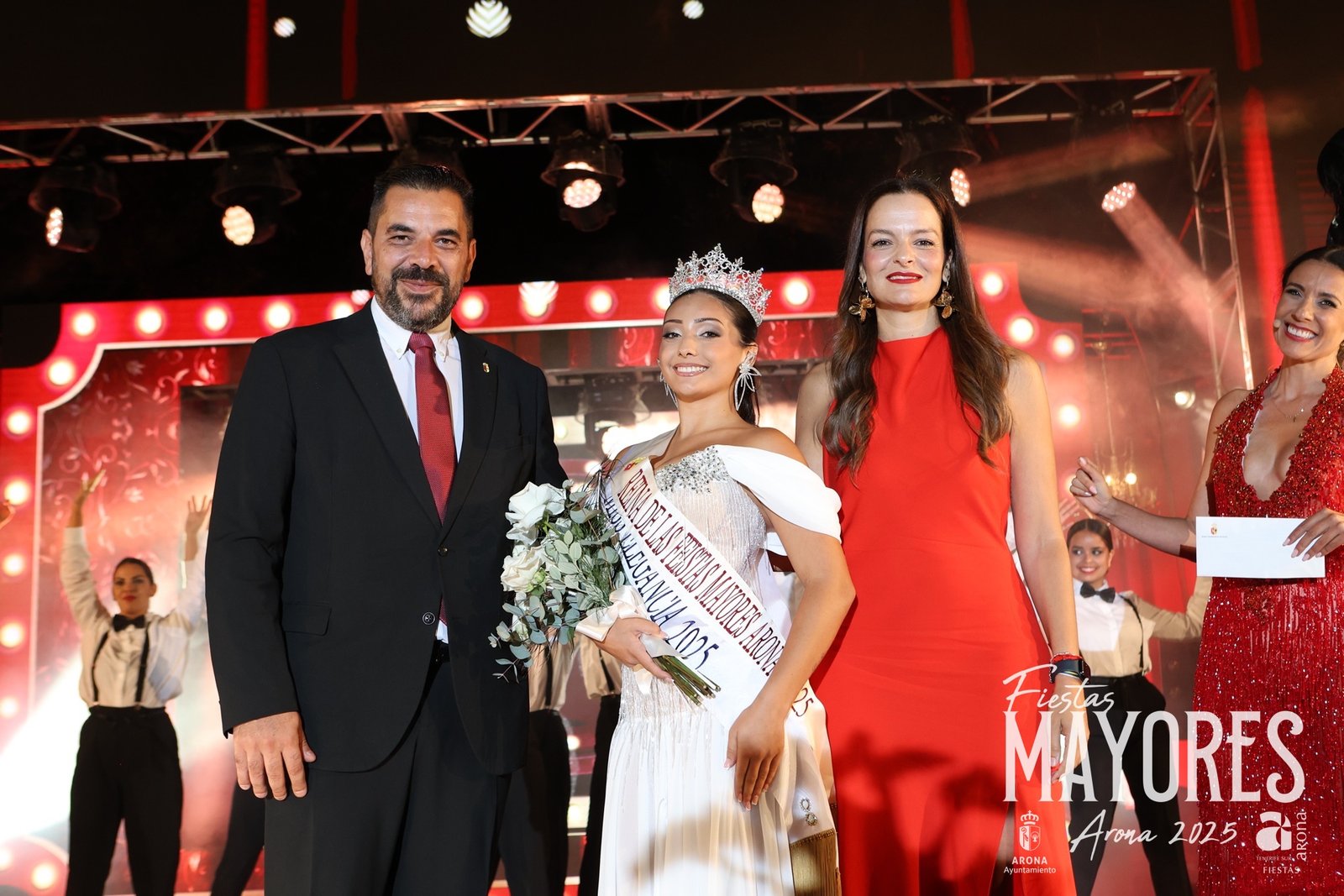 La joven Ainhoa Martín Reyes ha sido coronada como Reina de las Fiestas Mayores de Arona 2025 en honor al Santísimo Cristo de la Salud y Nuestra Señora del Rosario. Junto a ella, Elisa Cabello Valentín ha sido nombrada primera Dama de Honor y Marta García Bethencourt como Segunda Dama de Honor.