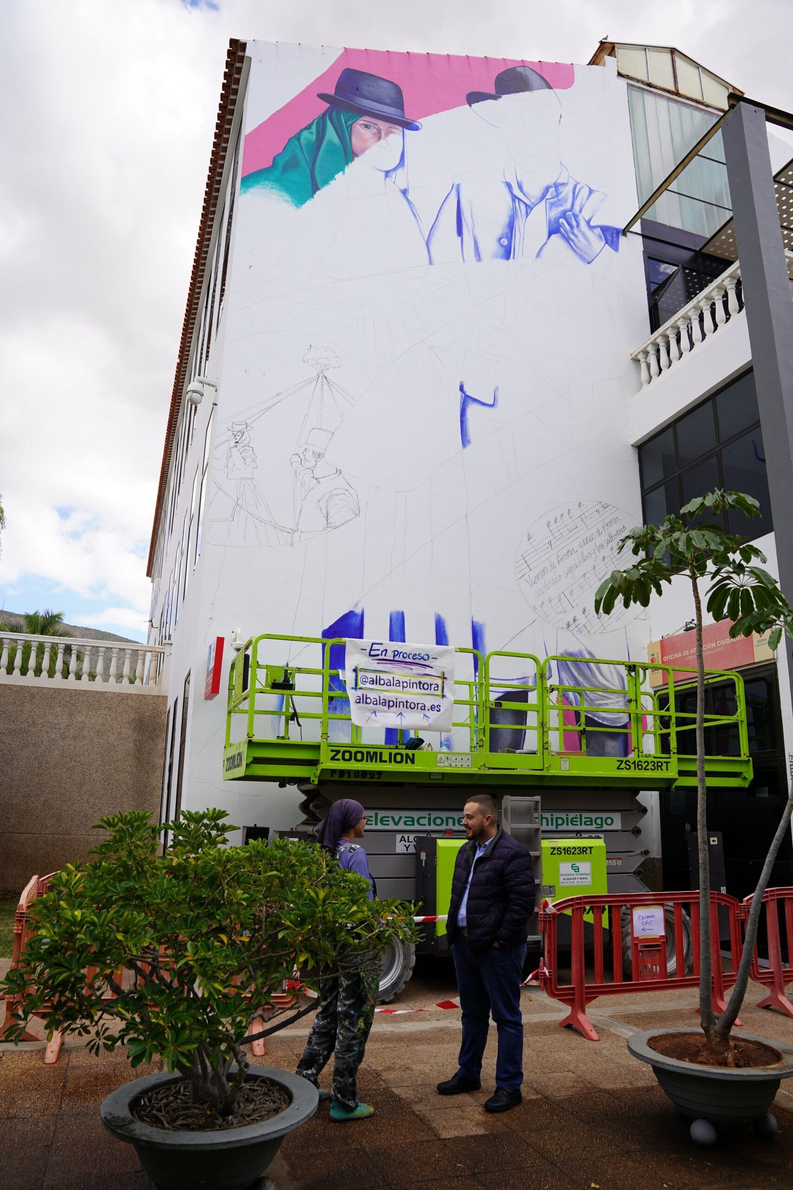 Arona embellece Los Cristianos con murales que resaltan su cultura

El municipio de Arona continúa promoviendo su riqueza cultural a través de la creación de nuevos murales en Los Cristianos. Estas intervenciones artísticas permanentes, ubicadas en el Centro Cultural de la localidad, buscan resaltar el folclore y la tradición musical de la zona.

Bajo la dirección del concejal Naím Yánez Alonso, el Ayuntamiento de Arona ha puesto en marcha esta iniciativa para embellecer el espacio público y promover las tradiciones locales. Los murales, que se están realizando en el Centro Cultural de Los Cristianos, formarán parte del entorno urbano de manera permanente.

El primer mural, ubicado en el lateral del edificio que da al Servicio de Atención a la Ciudadanía (SAC) de Los Cristianos, estará dedicado al traje de Chasna, el baile de cintas y el folclore tradicional del municipio. Además, incluirá una estrofa de una seguidilla y saltona relacionada con Arona.

Por otro lado, el segundo mural, que se ubicará en otro espacio exterior del centro cultural, rendirá homenaje a la tradición musical y bandística de Arona. Con estas iniciativas, el municipio busca enriquecer su patrimonio cultural y promover el arte en espacios públicos para el disfrute de residentes y visitantes.